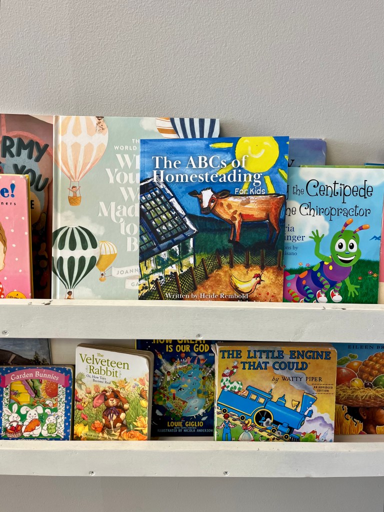 The ABCs of Homesteading for Kids on a book shelf with other books